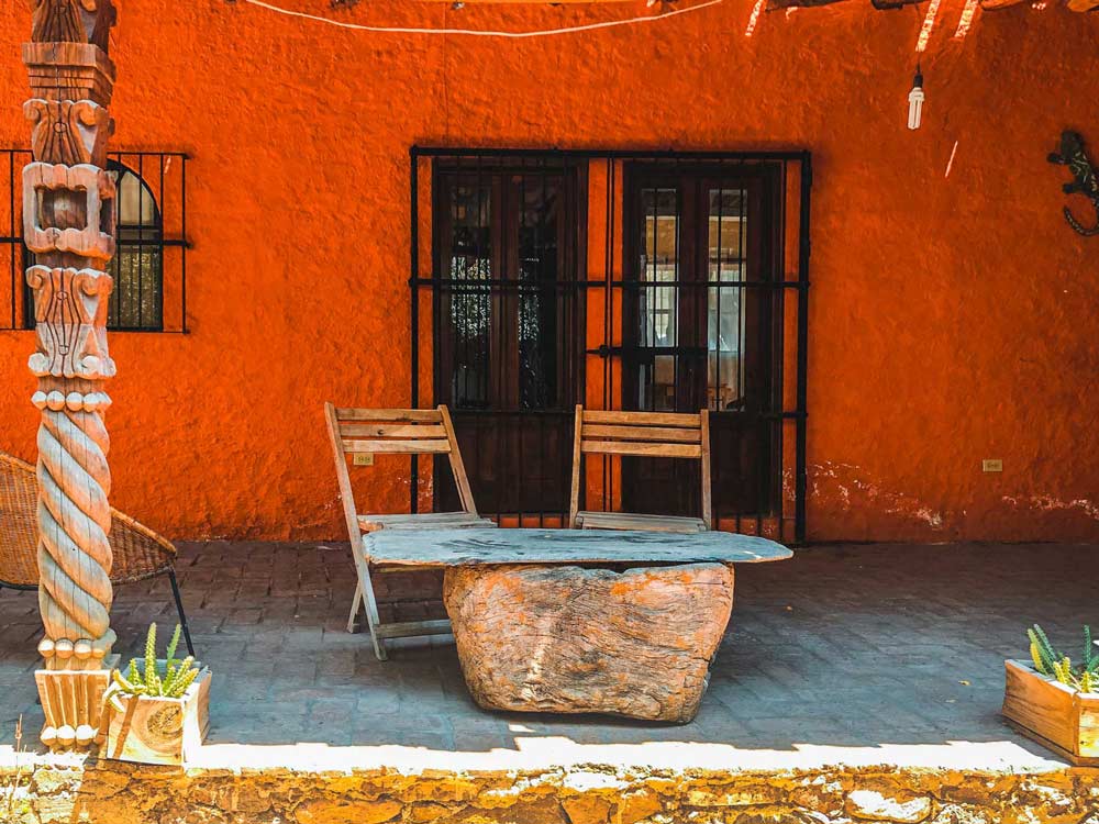 Red exterior of casa safta with 2 chairs and a table made of stones on the patio