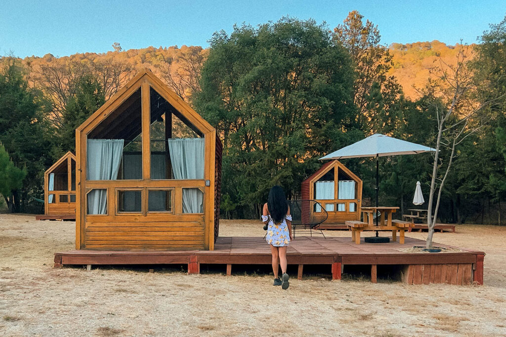 Cabin the woods of Amealco de Bonfil with a girl standing facing the cabins
