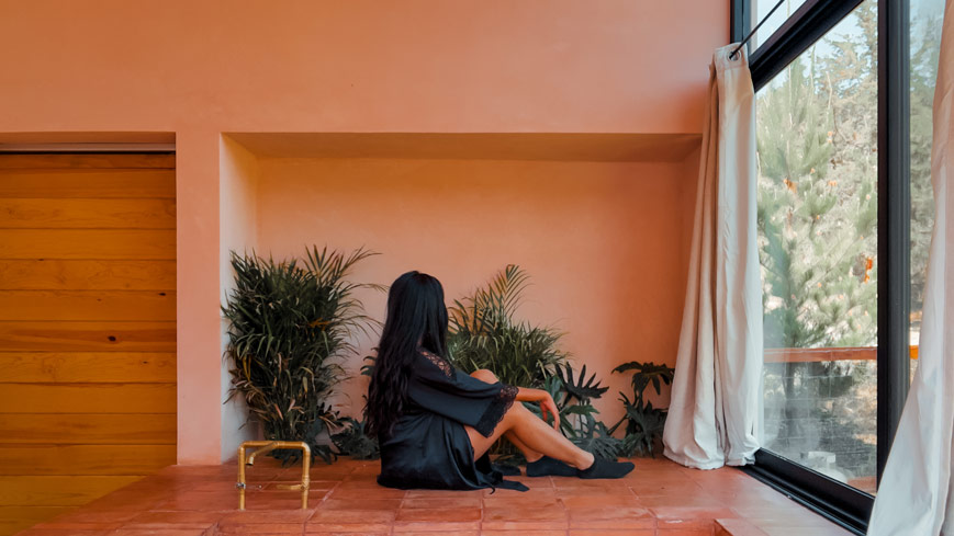 Himanshi Shah sitting next to the hot tub of La Comuna, with a large window o the right