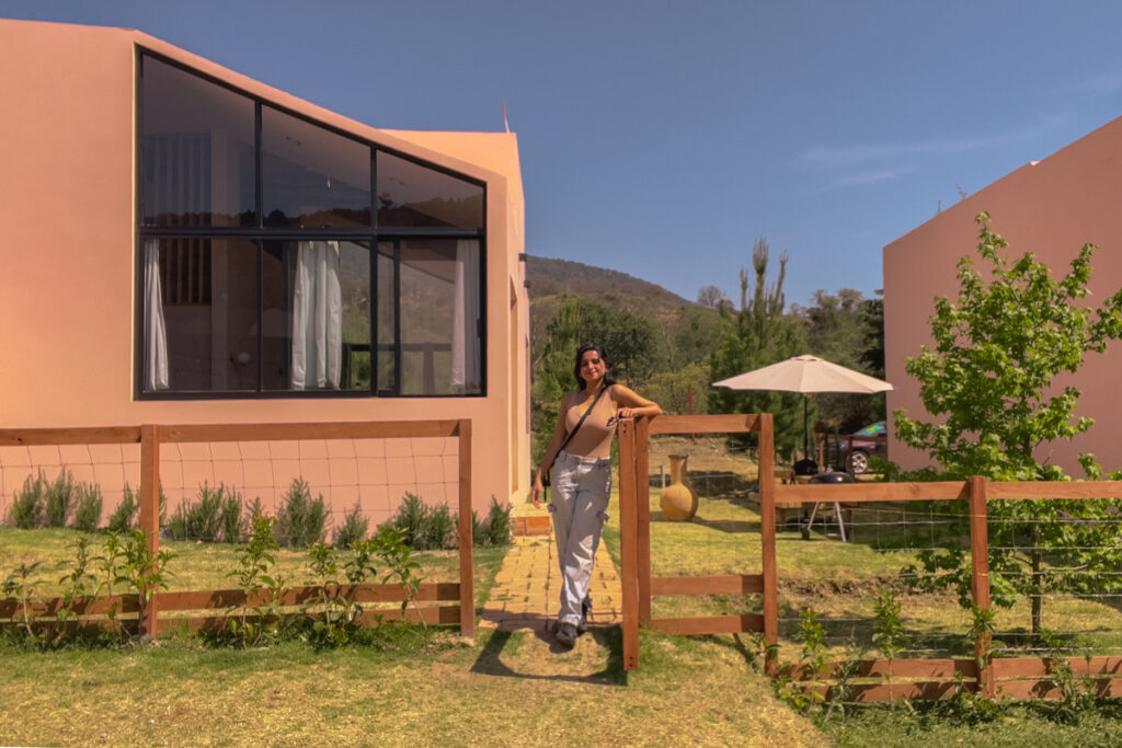Travel influencer Himanshi Shah, standing at the entrance of the gate to the Pink House of La Comuna, in Amealco de Bonfil