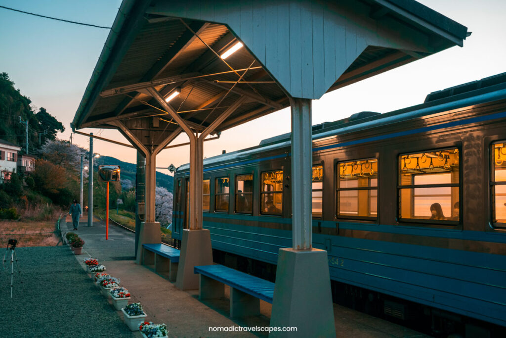 Blue train pulling in at Shimonada Station at sunset, in Ehime Prefecture