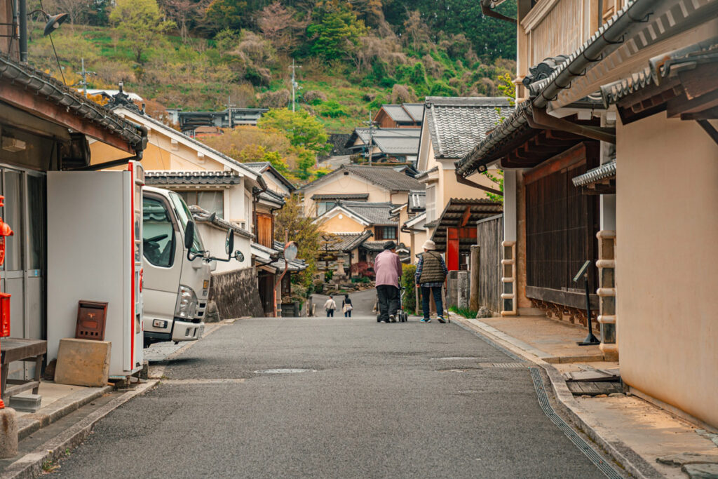 Two old Japanese grandmothers walking together in the Main Street of Uchiko